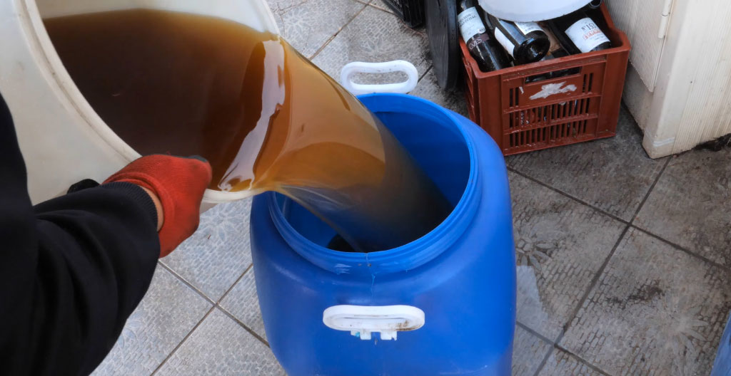 Technicien spécialisé en gilet de sécurité procédant à la collecte d'huiles de cuisson usagées avec équipement professionnel et véhicule de collecte agréé